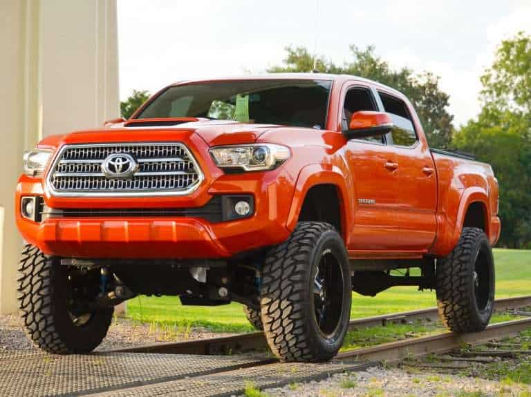 aftermarket 3rd gen tacoma mods on a orange tacoma sitting on railroad tracks