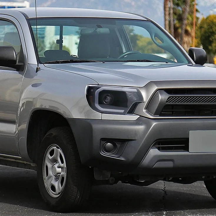 A gray off-road pickup truck equipped for off-road driving, featuring durable tires and rugged design suitable for challenging terrains, parked outdoors.