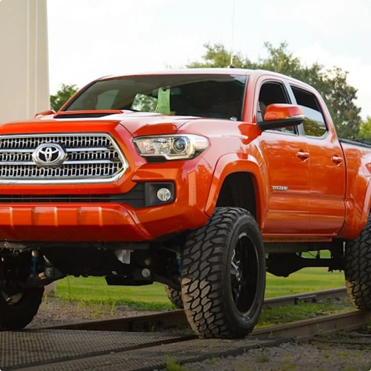 aftermarket 3rd gen tacoma mods on a orange tacoma sitting on railroad tracks