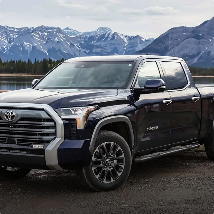 A black Toyota Tundra parked near a lake with mountain views, ideal for off-road and outdoor activities.